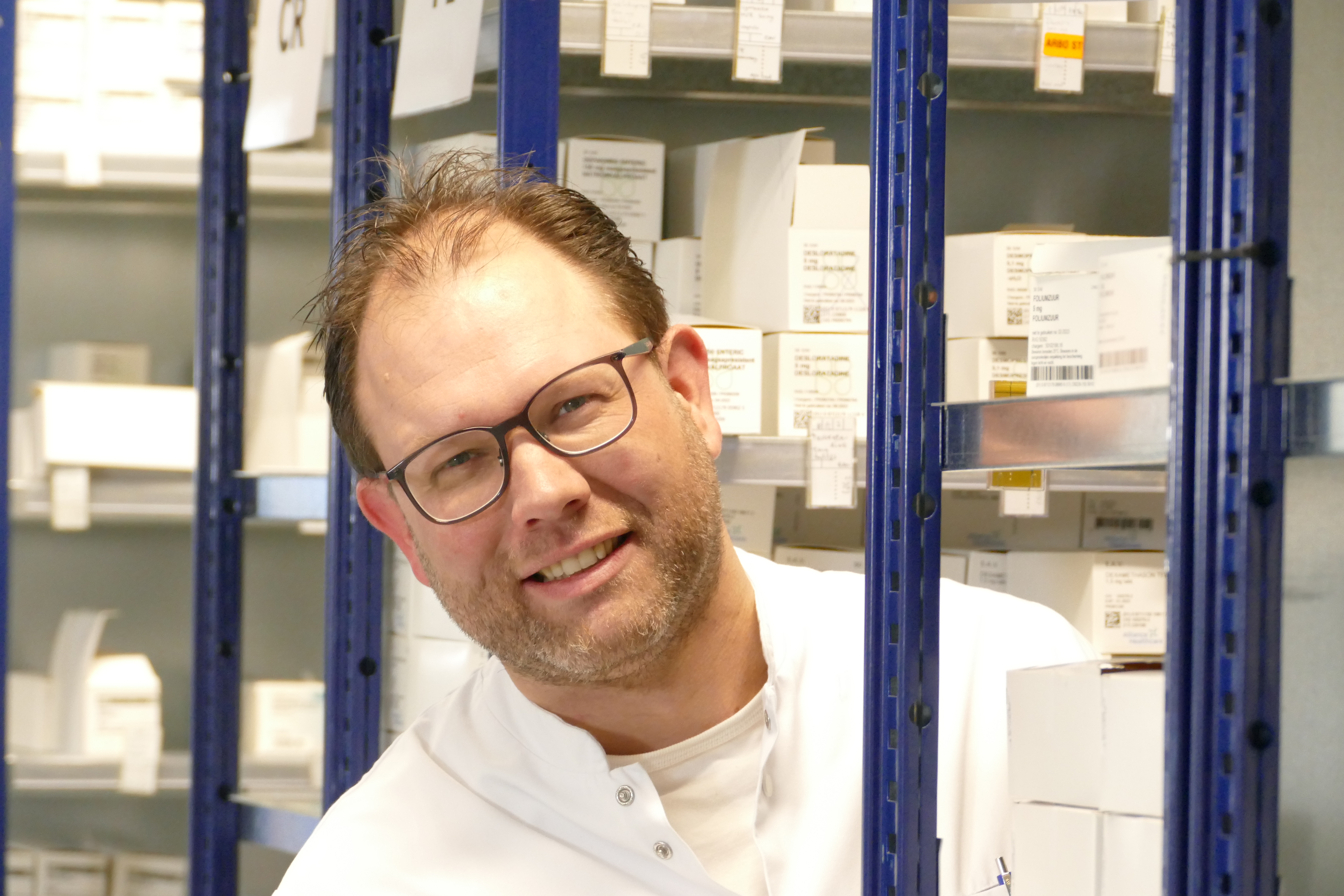 Rien Hoge (alleen voor de foto zonder mondkapje) tussen de medicatie in de ziekenhuisapotheek.