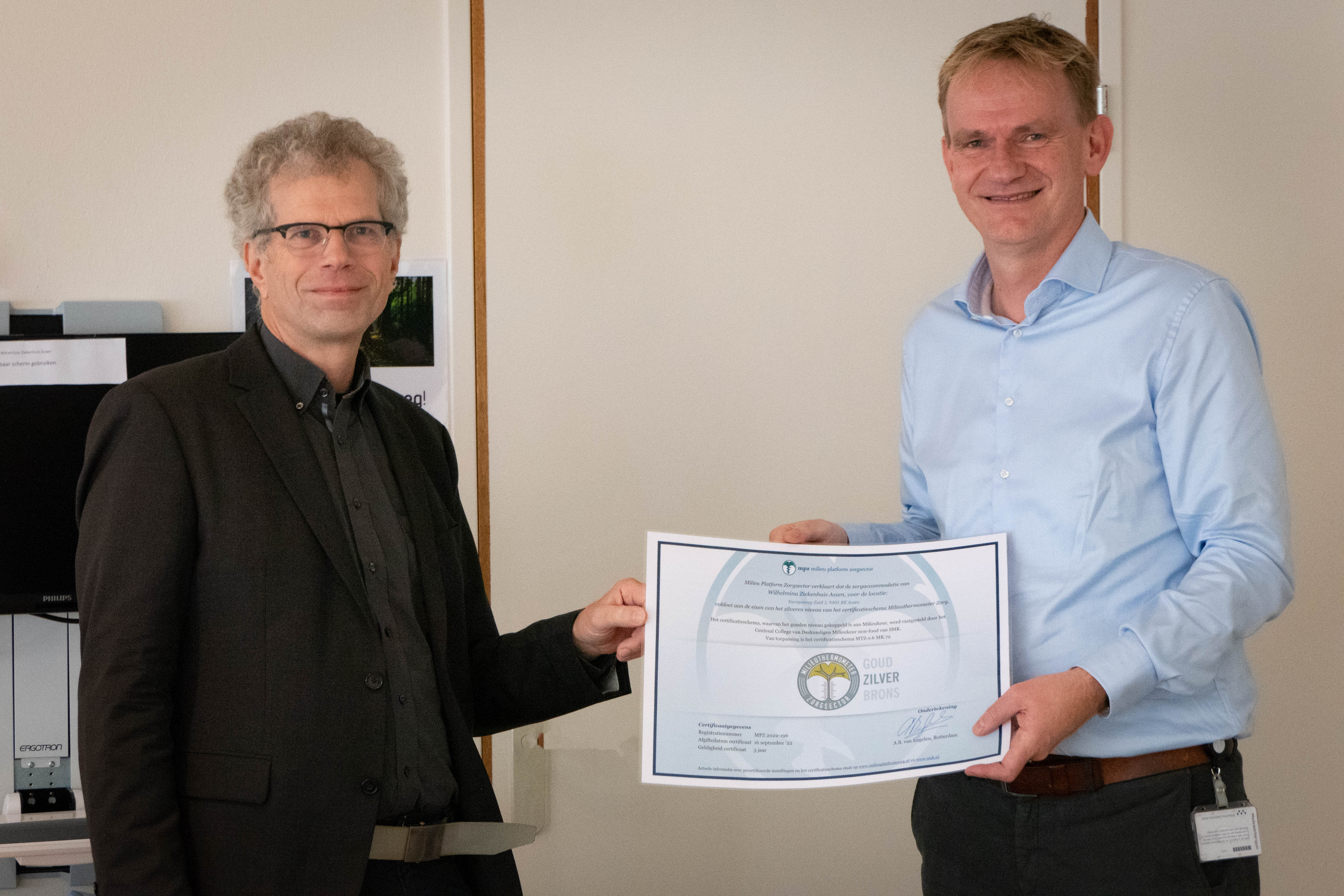 Hans Mulder (r) ontvangt het 'zilveren' certificaat uit handen van dhr. Van Engelen, directeur van Milieu Platform Zorgsector.